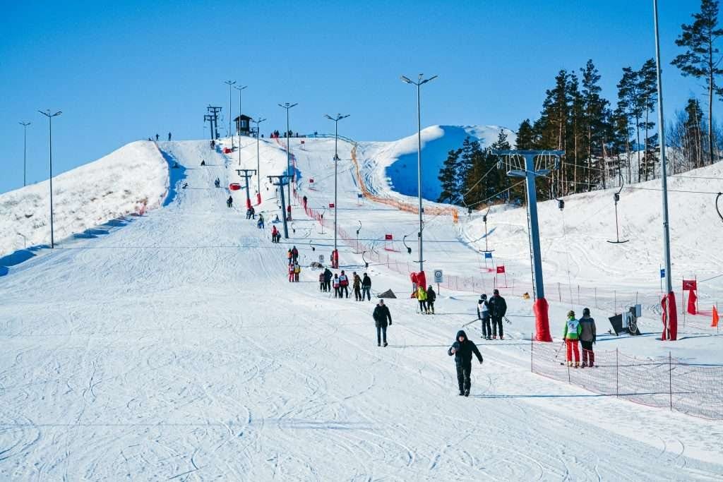 Ski resort with travelers enjoying the slopes and ski lifts. Travelers skiing and walking on a snowy slope