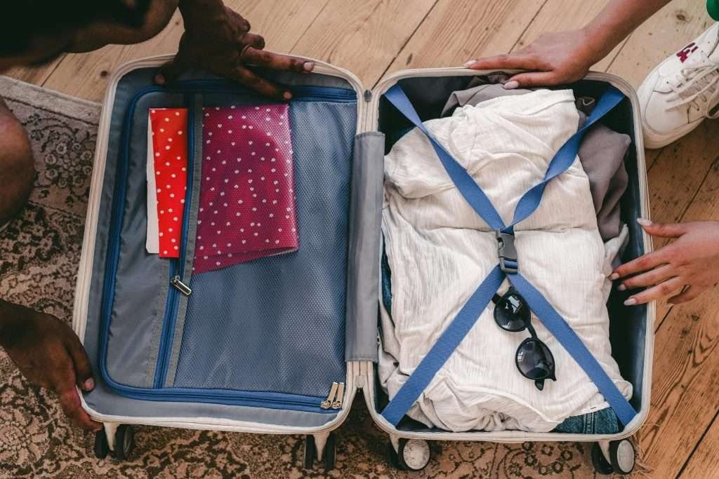 Travelers packing essentials into a small suitcase