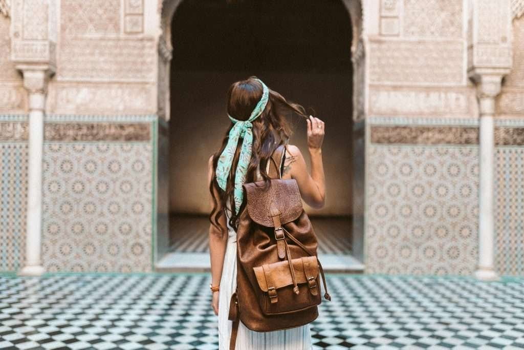 Back view of a traveler in a headscarf at a cultural heritage Solo traveler admiring intricate architecture during her journey