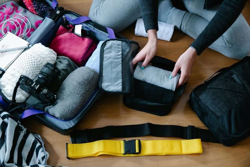 Open suitcase with clothes, a camera, and travel essentials Traveler using packing cubes for efficient luggage organization