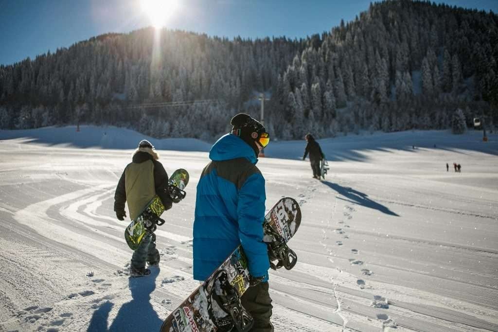Group of travelers heading to a ski run on a bright sunny day Travelers walking with snowboards across a snowy mountain slope