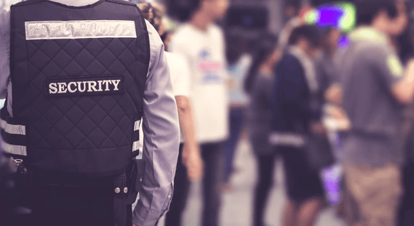 Close-up of a security officer in uniform monitoring a busy crowd in a public space.