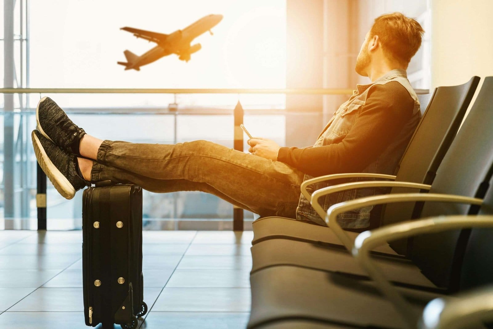 man at airport with legs on carryon luggage