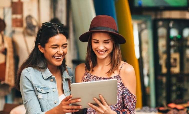 two woman smiling infront of computer