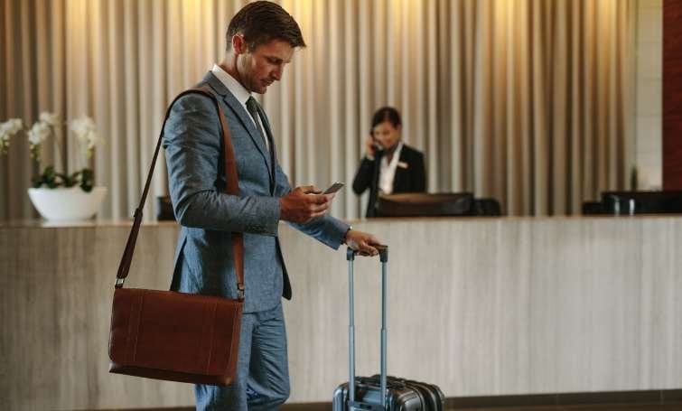 A traveler checking in at a hotel reception with a rewards card
