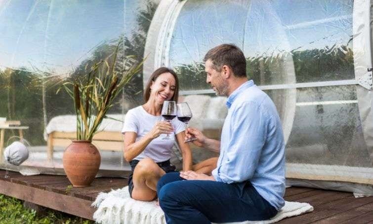 couple drinking wine outside glamping pod