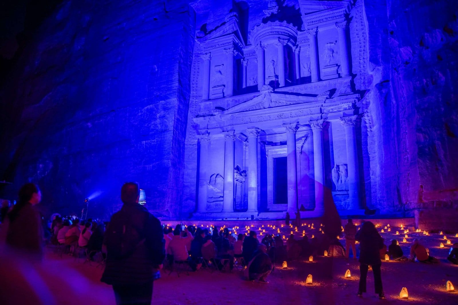 A diverse group of travelers viewing Petra at night
